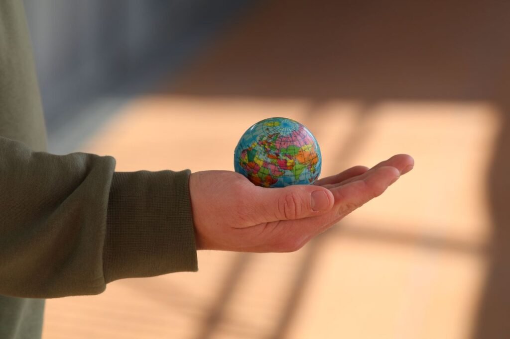 pexels-photo-7532231-7532231 Close-up of a hand holding a small globe with blurred background, emphasizing depth and exploration.